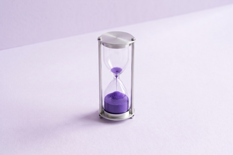 Hourglass with violet sand, most of it in the lower bulb