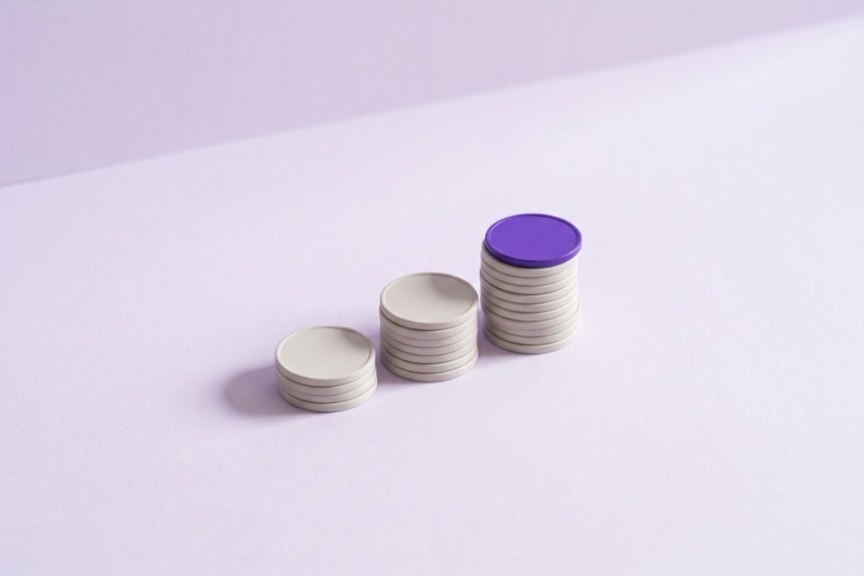 Three stacks of blank coins rising in height, the tallest topped with a violet coin
