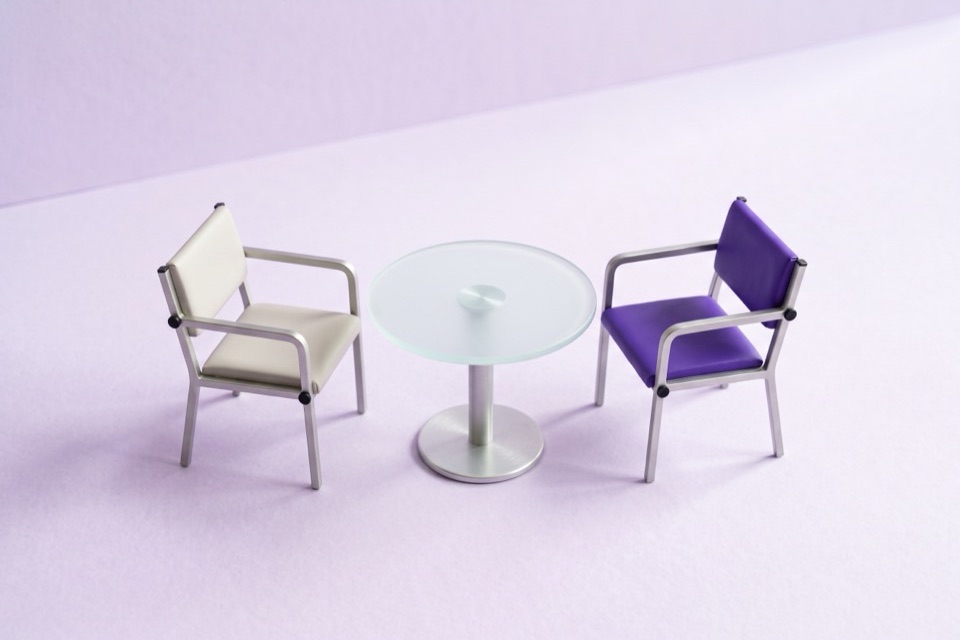 Two chairs facing each other across a small glass table, one chair violet