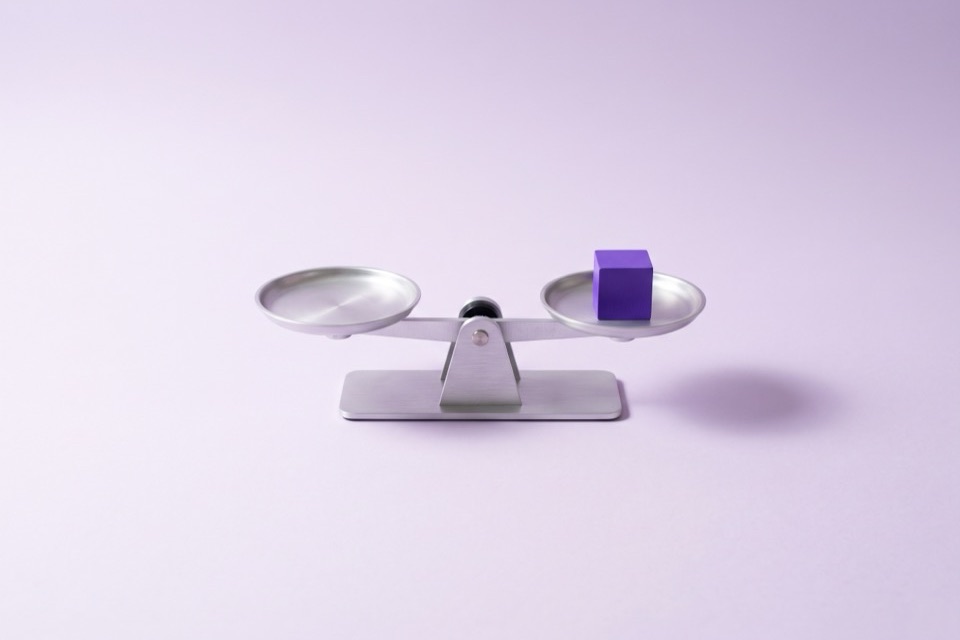 Aluminum balance scale with a violet cube in one pan