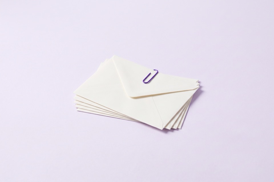 Stack of blank envelopes held together by a violet paper clip